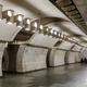an epty. subway station wit curved white marble walls and a row of lights